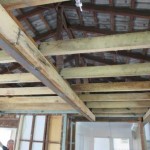 Pitched roof framing exposed to show ceiling joists, rafters, roof battens and roof tiles.